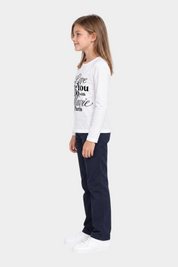 Bambina indossa t-shirt bianca a maniche lunghe Follower SRL con scritta gioiello in strass neri e pantaloni blu