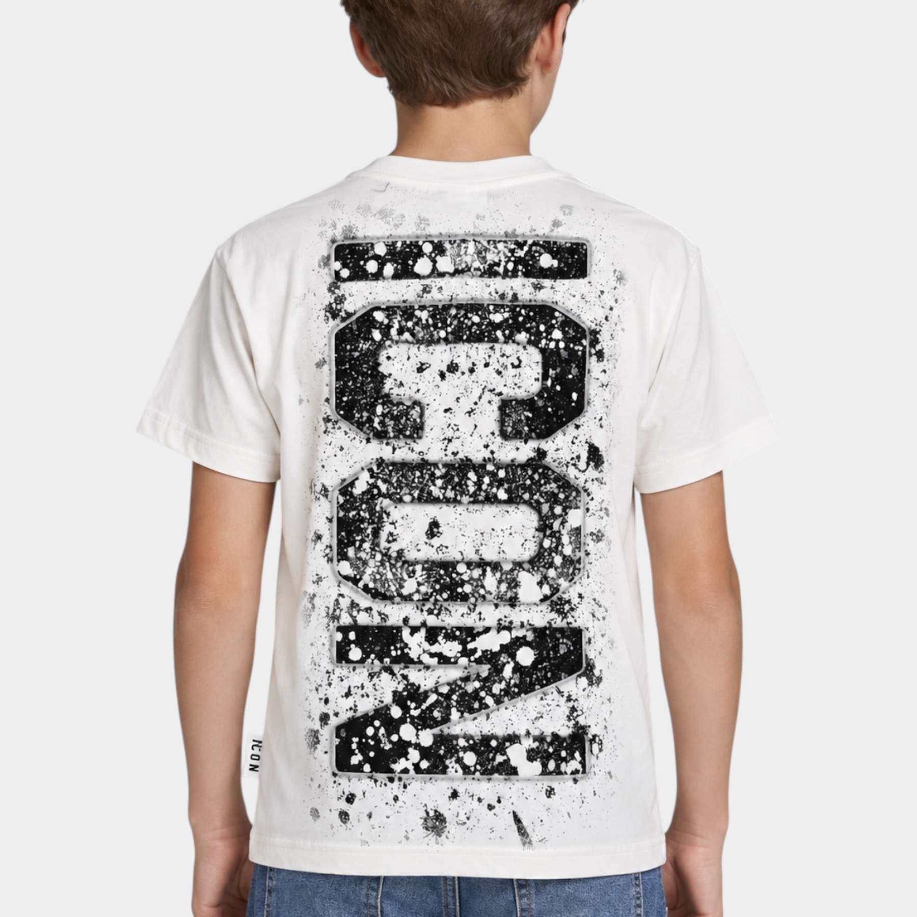 Ragazzo indossa una t-shirt bianca Follower SRL con grande stampa nera ICON effetto schizzi di vernice sul retro