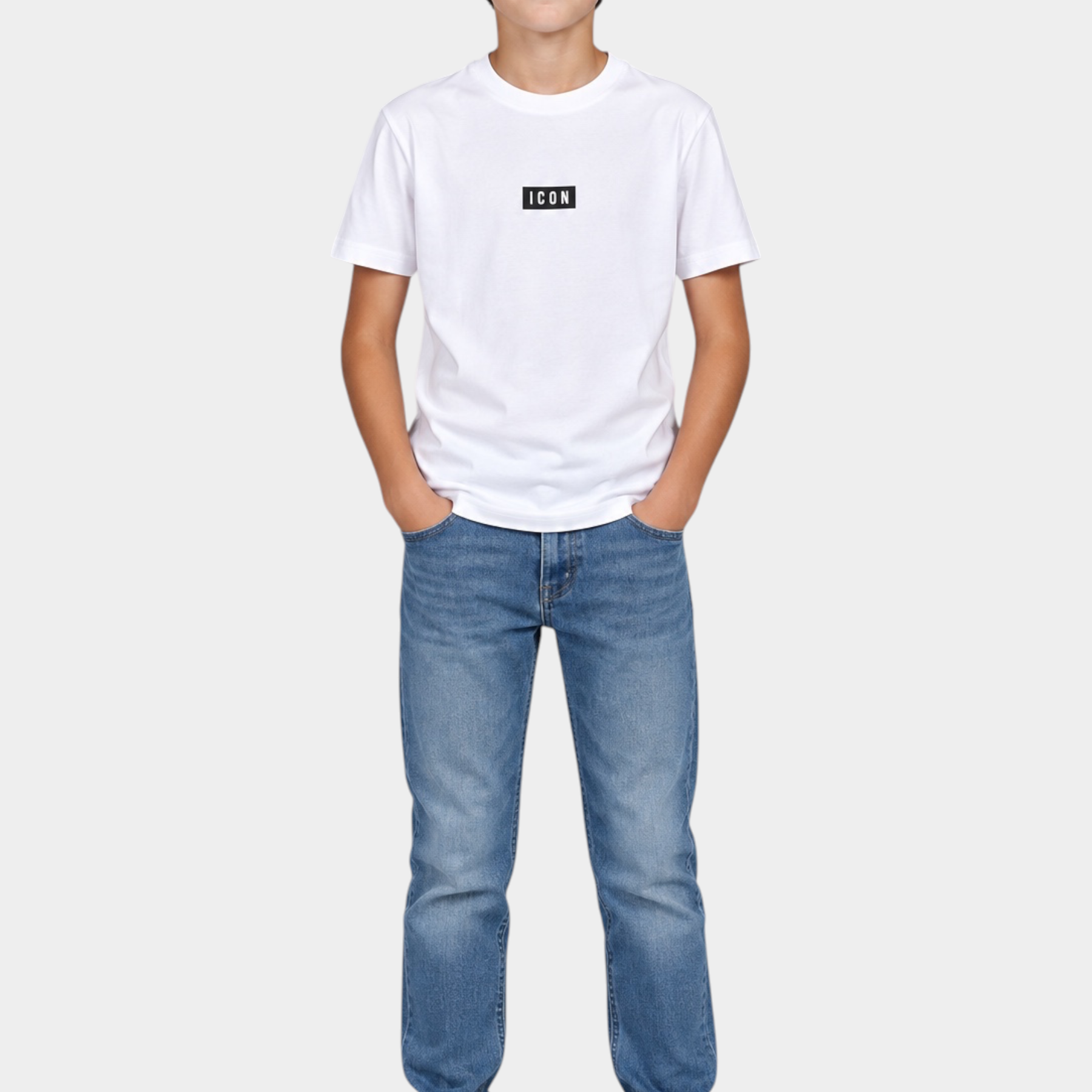 Ragazzo indossa una t-shirt bianca Follower SRL con logo ICON nero, jeans blu e sneakers bianche su sfondo grigio