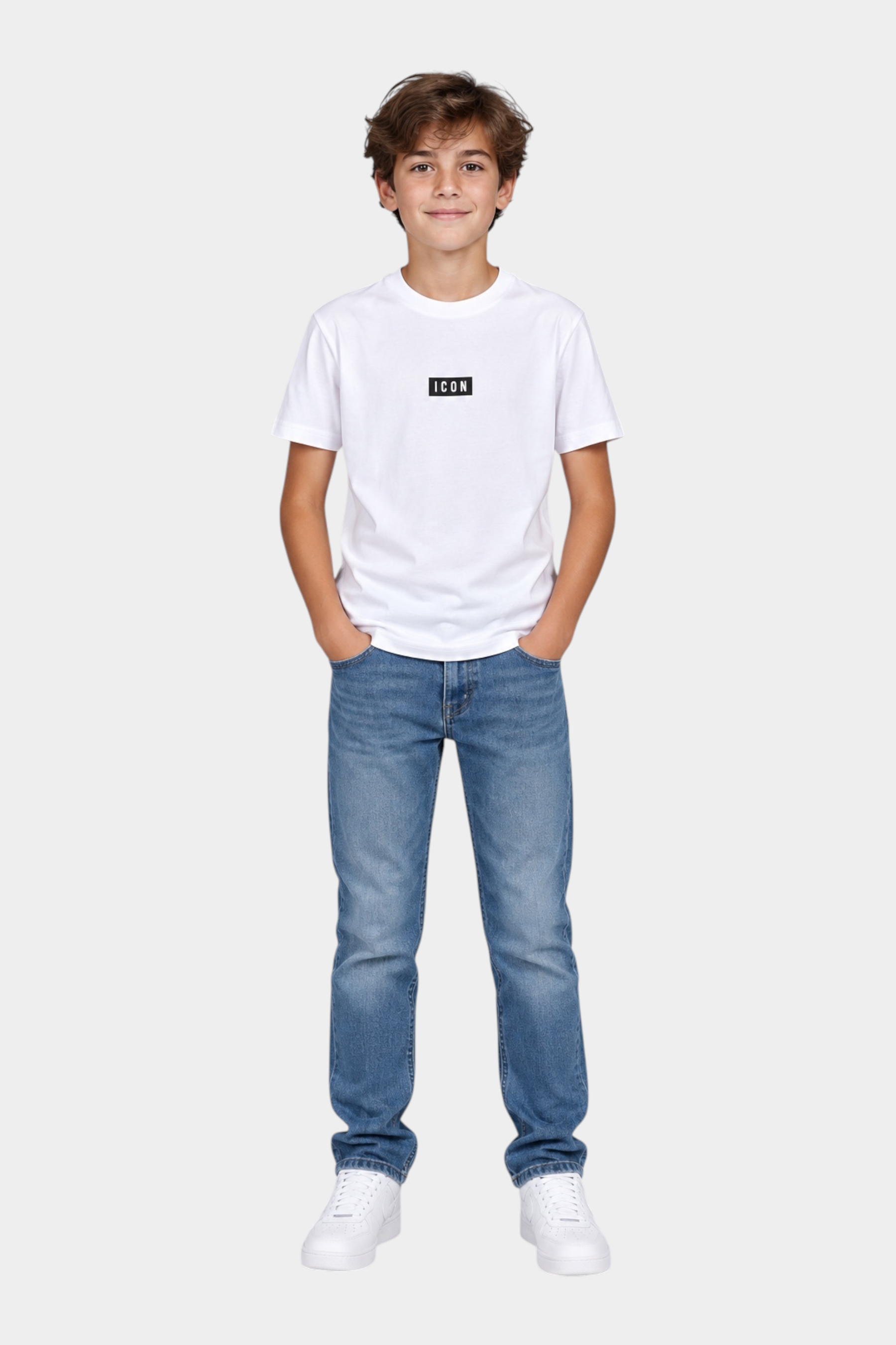 Ragazzo indossa una t-shirt bianca Follower SRL con logo ICON nero, jeans blu e sneakers bianche su sfondo grigio
