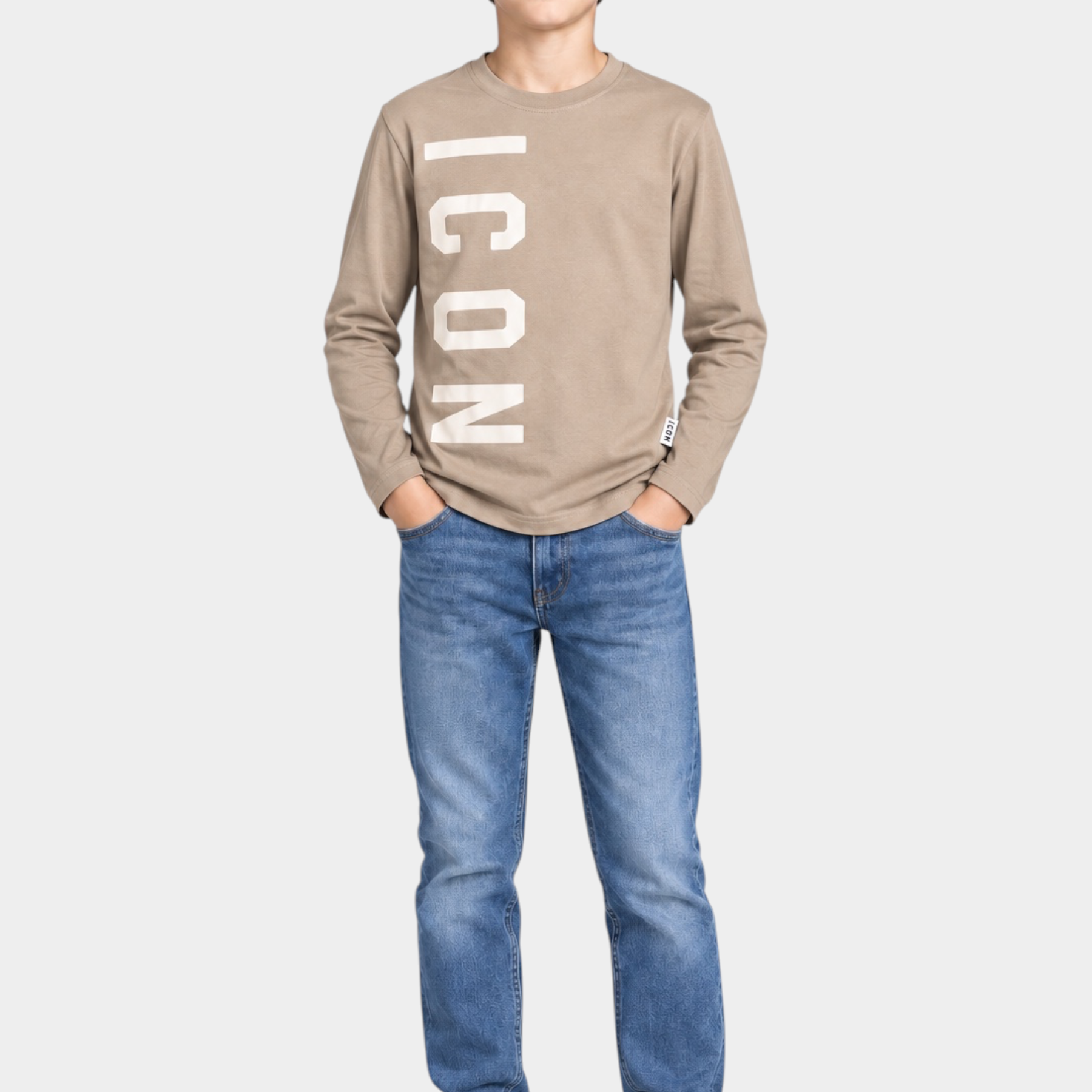 Ragazzo indossa Follower SRL t-shirt beige a maniche lunghe con stampa ICON bianca, jeans blu e sneakers bianche