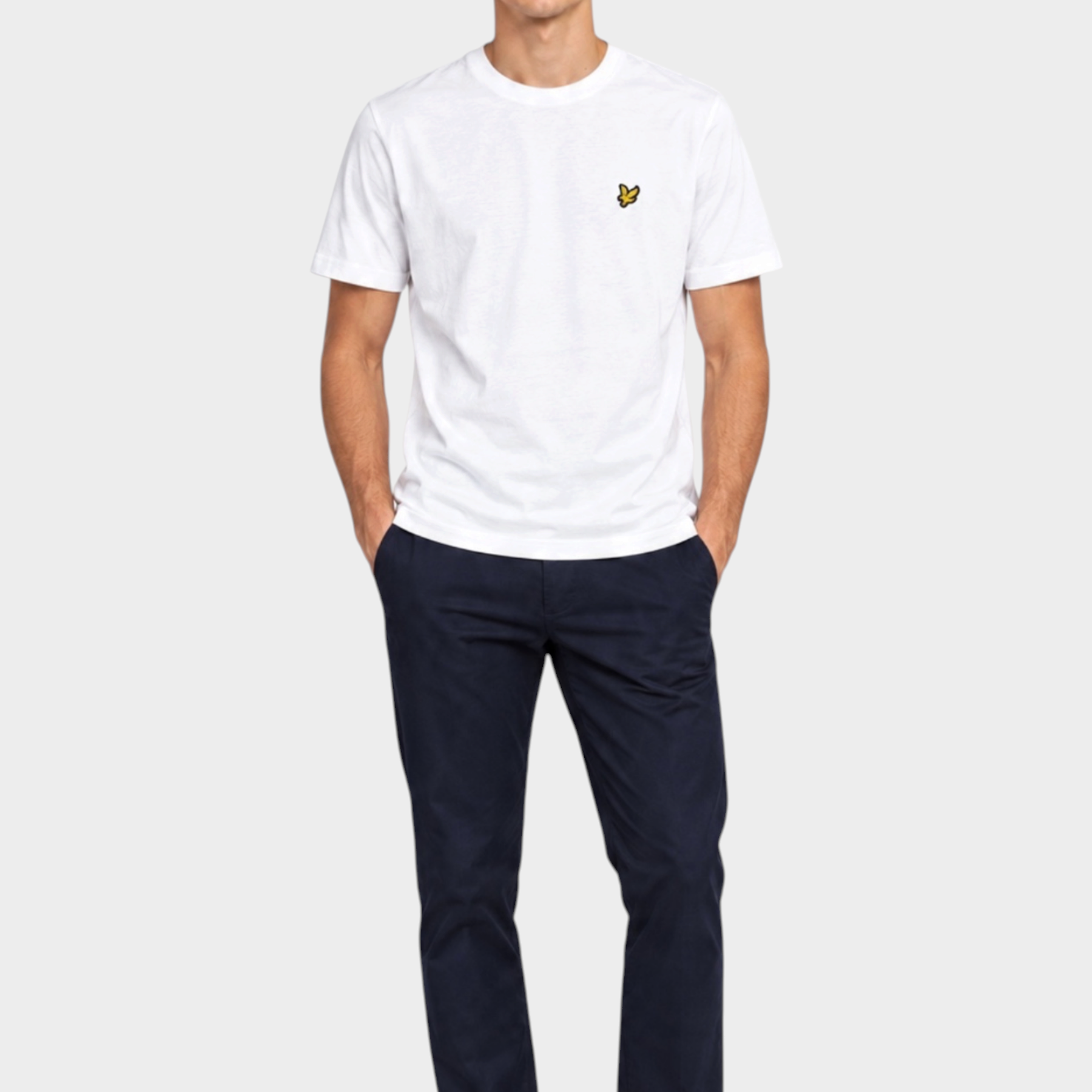 Modello indossa t-shirt bianca Follower SRL Lyle & Scott con logo dorato sul petto e pantaloni blu scuro