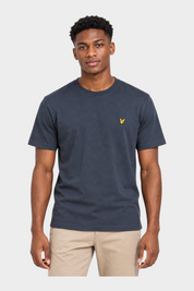 Modello indossa una t-shirt blu scuro Follower SRL con logo giallo sul petto e pantaloni beige