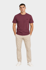 Modello indossa t-shirt bordeaux LYLE & SCOTT con logo ricamato, abbinata a pantaloni chino beige, Follower SRL