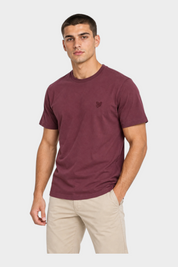 Modello indossa t-shirt bordeaux Follower SRL con logo ricamato sul petto e girocollo, abbinata a pantaloni beige