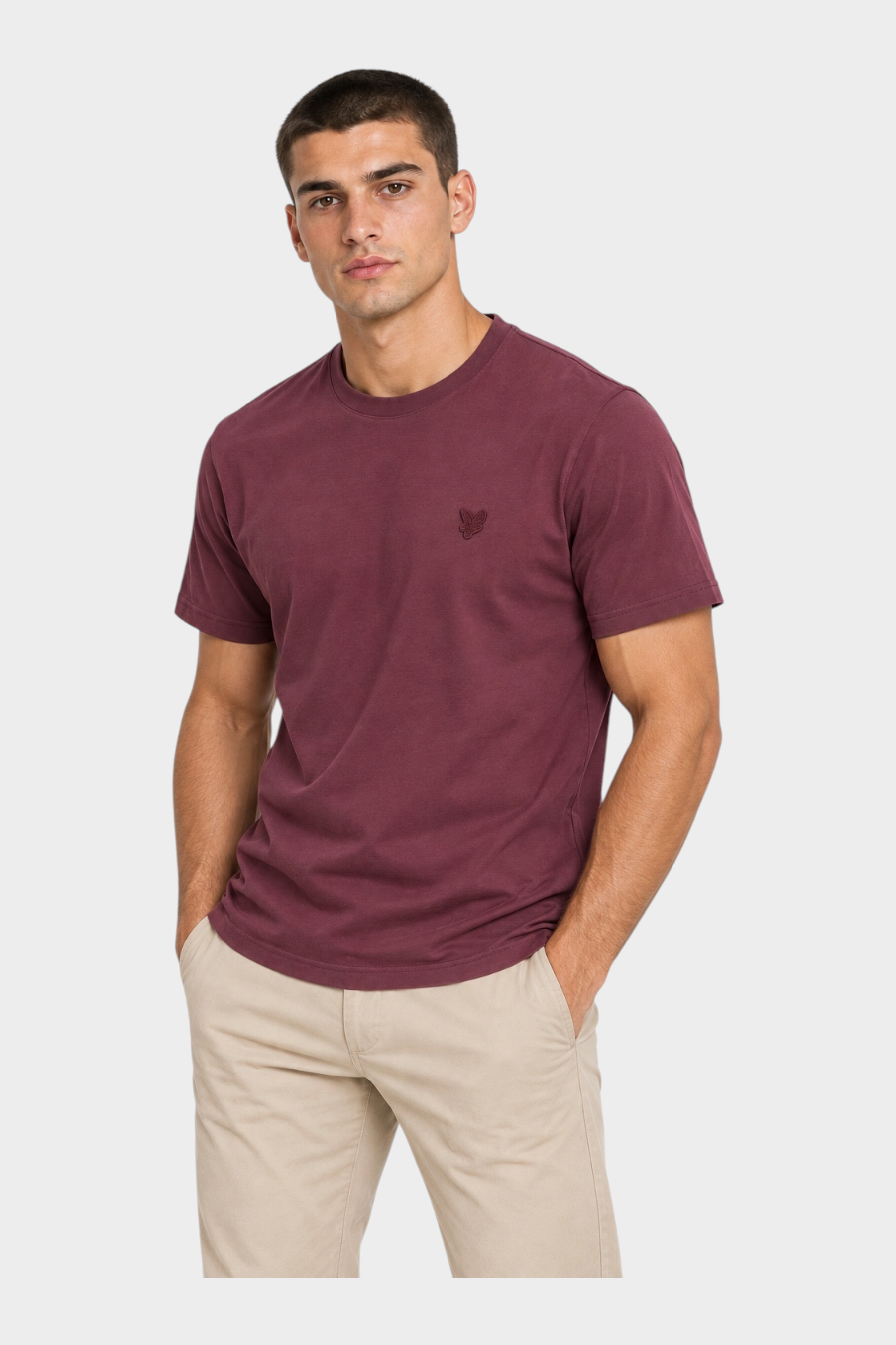 Modello indossa t-shirt bordeaux Follower SRL con logo ricamato e girocollo, abbinata a pantaloni beige