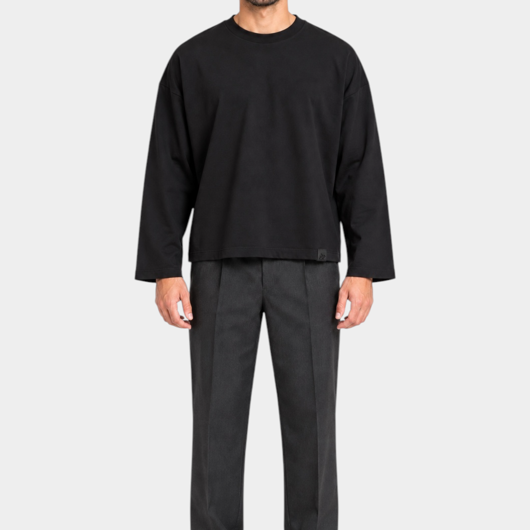 Modello indossa t-shirt nera a manica lunga boxy fit di Follower SRL con pantaloni grigi e scarpe nere