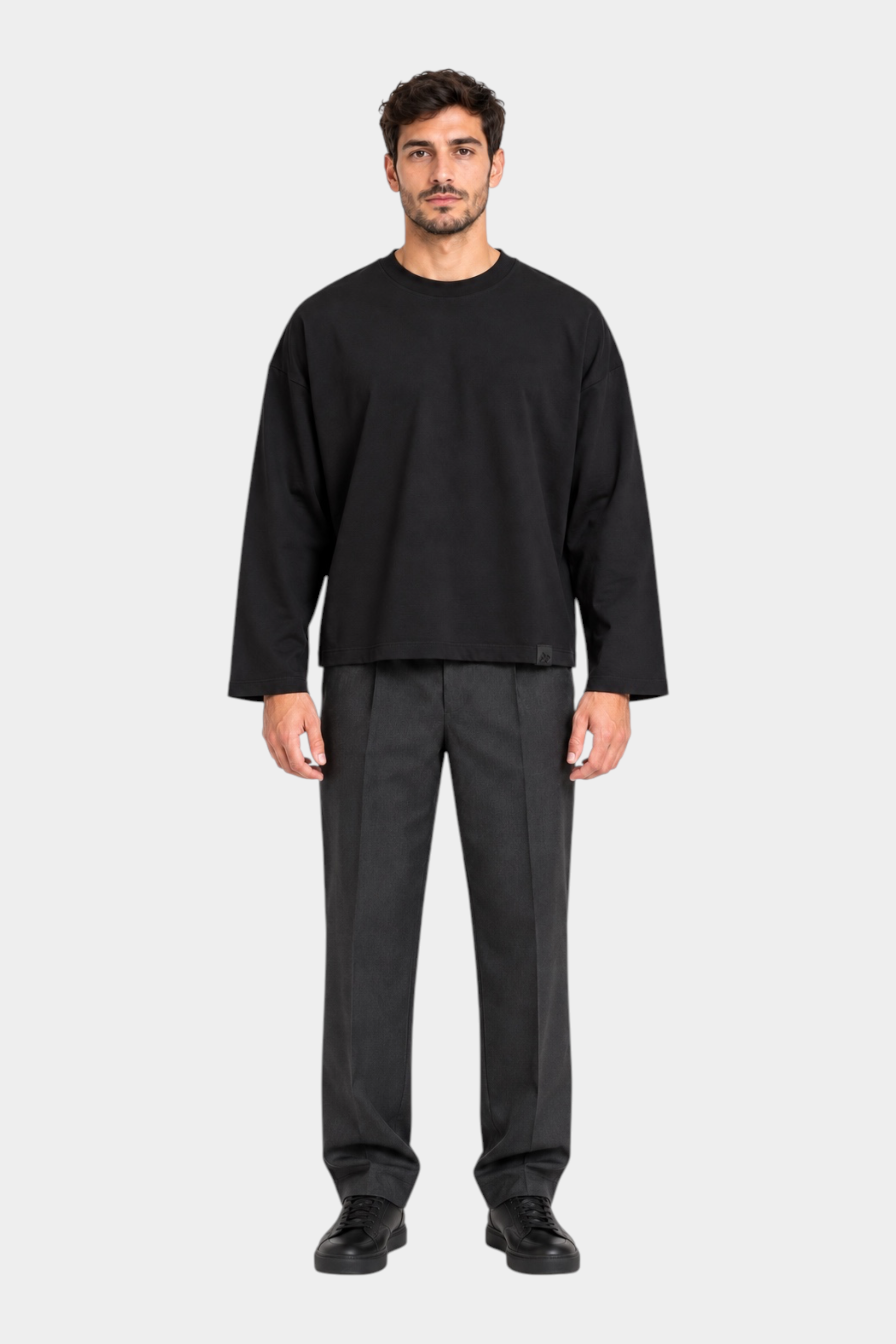 Modello indossa t-shirt nera a manica lunga boxy fit di Follower SRL con pantaloni grigi e scarpe nere