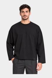 Modello indossa t-shirt nera a maniche lunghe Follower SRL con vestibilità boxy e girocollo su sfondo bianco