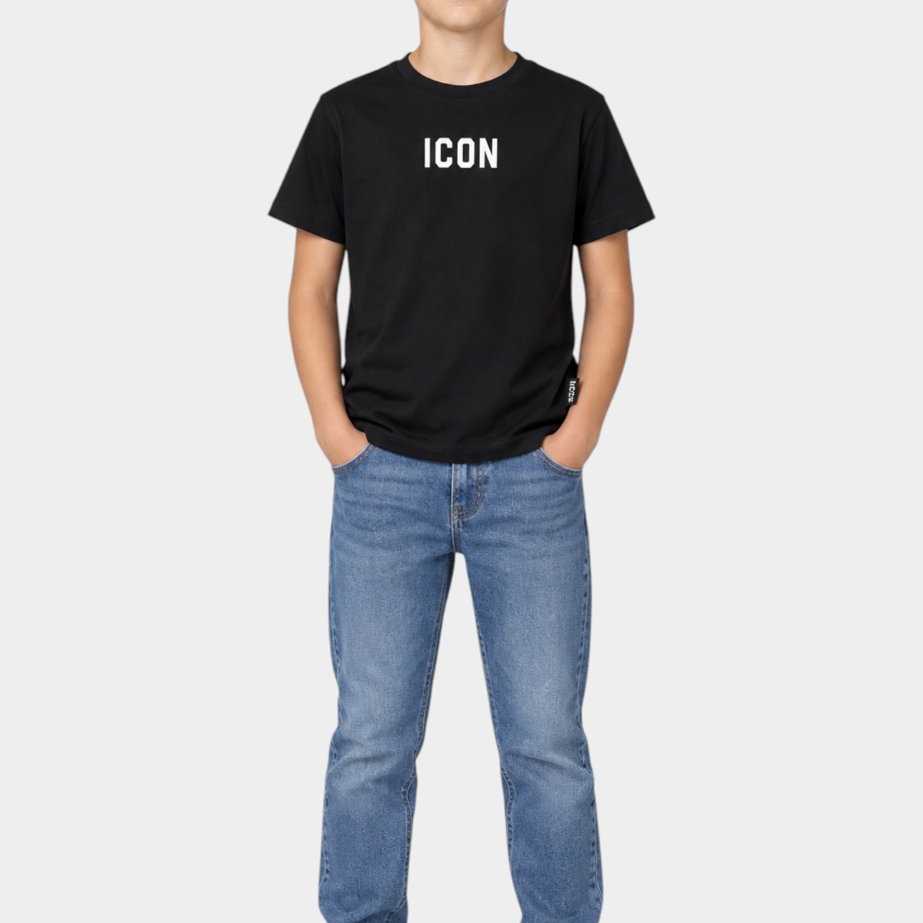 Ragazzo indossa una T-shirt nera Follower SRL con scritta ICON bianca, jeans blu e sneakers bianche