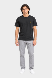Modello indossa t-shirt nera Follower SRL Lyle & Scott con logo giallo sul petto e pantaloni grigi
