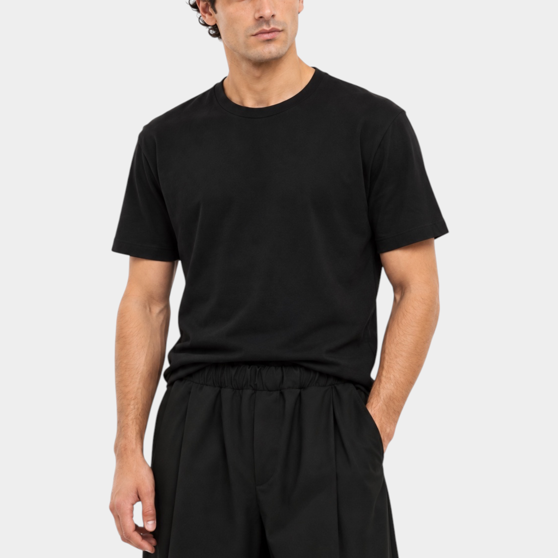 Modello indossa t-shirt nera a girocollo regular fit di Follower SRL con pantaloni neri su sfondo bianco