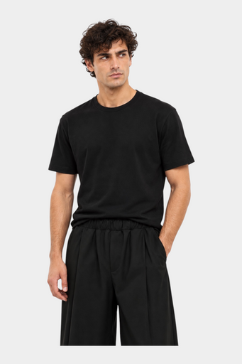 Modello indossa t-shirt nera a girocollo regular fit di Follower SRL con pantaloni neri su sfondo bianco