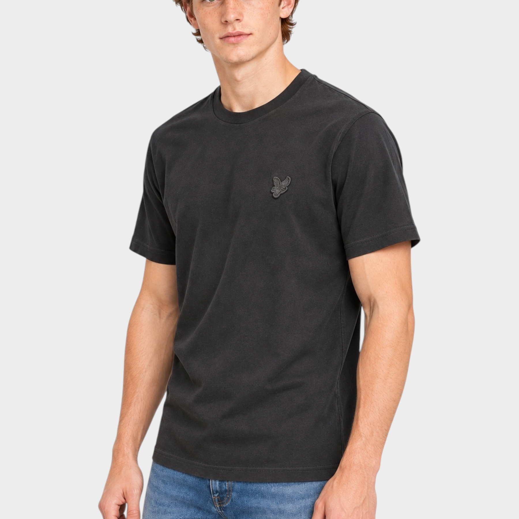 Modello indossa t-shirt nera in cotone Follower SRL con logo Lyle & Scott sul petto e jeans blu