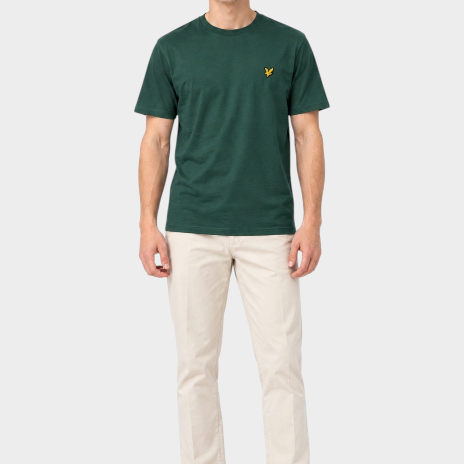 Modello indossa t-shirt verde Follower SRL con logo giallo sul petto, abbinata a pantaloni beige e scarpe bianche