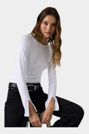 Modella indossa un top bianco a maniche lunghe Follower SRL con dettagli in pizzo sui polsini e scollo rotondo