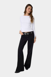 Modella indossa top bianco a maniche lunghe con dettagli in pizzo e jeans neri a zampa Follower SRL