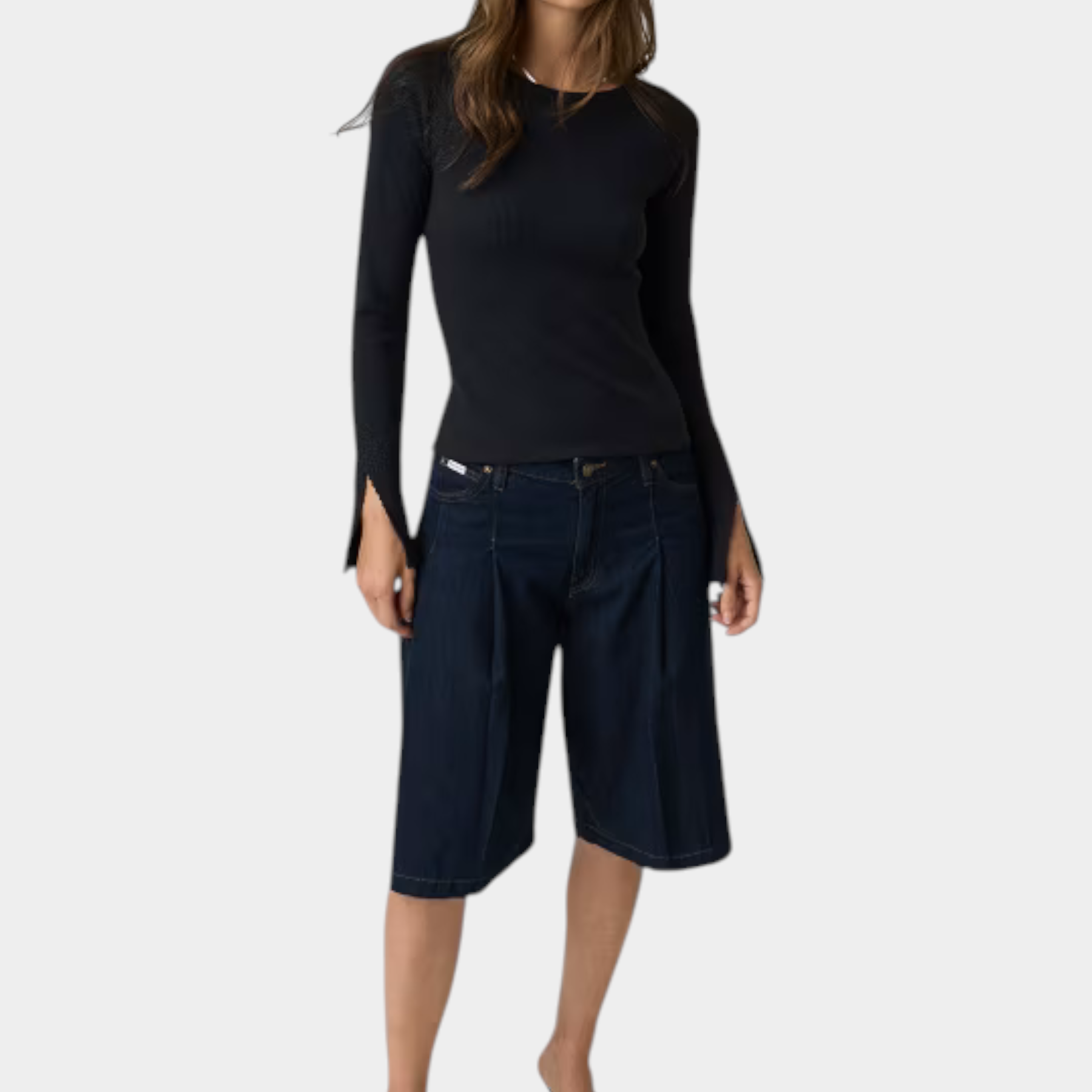 Modella indossa top nero a maniche lunghe con dettagli in pizzo Follower SRL abbinato a bermuda in denim scuro