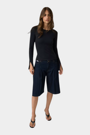 Modella indossa top nero a maniche lunghe con dettagli in pizzo Follower SRL abbinato a bermuda in denim scuro