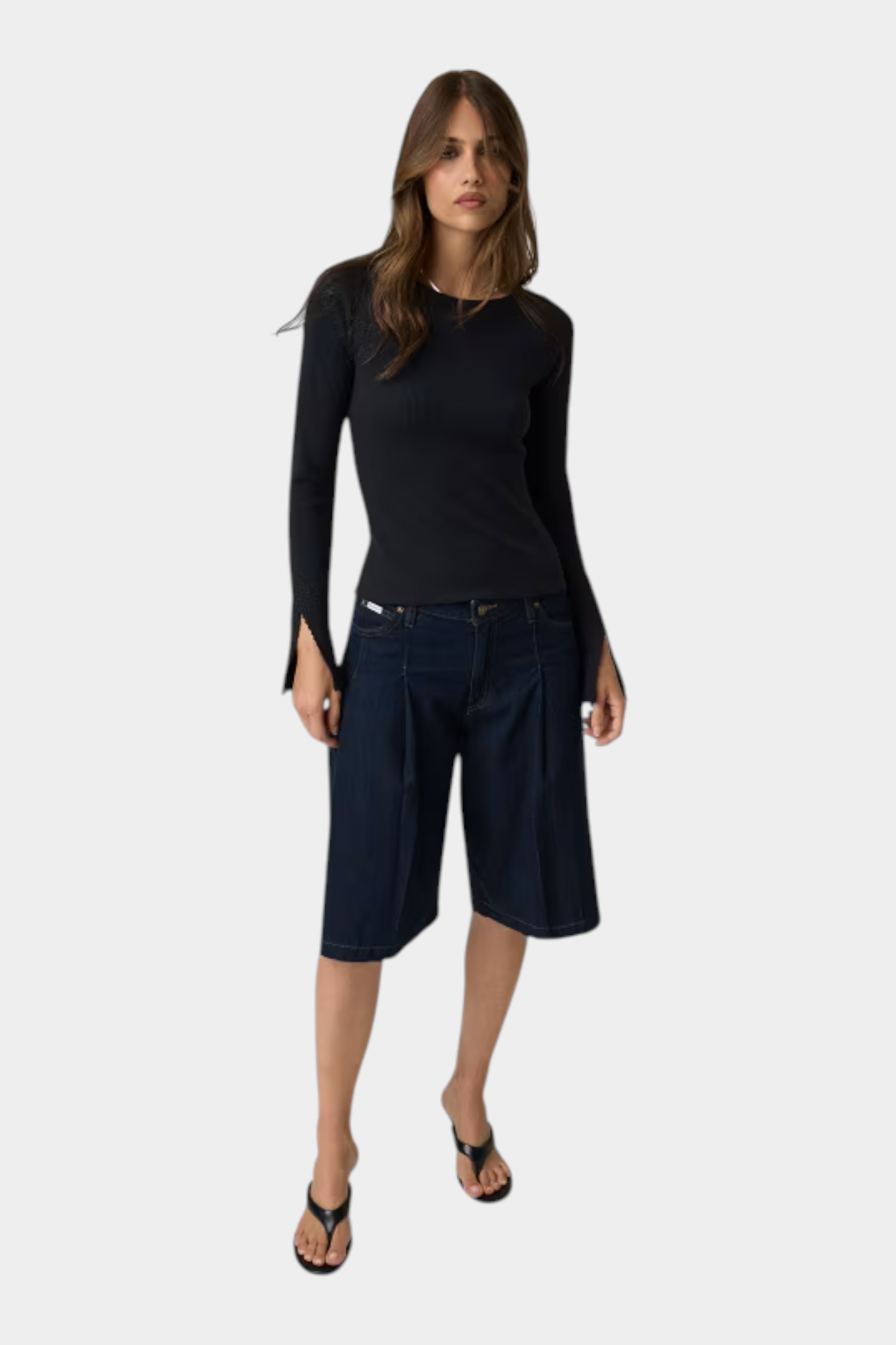 Modella indossa top nero a maniche lunghe con dettagli in pizzo Follower SRL abbinato a bermuda in denim scuro