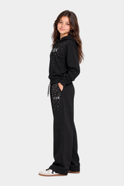 Bambina indossa tuta Follower SRL nera con cappuccio e strass decorativi sulla scritta ICON e sui pantaloni