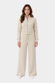Modella indossa tuta Follower SRL GUESS color ecru con felpa full zip e pantaloni a gamba larga con logo 4G