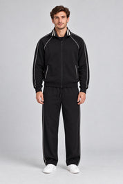 Modello indossa tuta sportiva nera Follower SRL con dettagli a righe bianche su giacca e pantaloni jogger