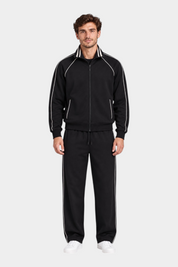 Modello indossa tuta sportiva nera Follower SRL con dettagli a righe bianche su giacca e pantaloni jogger