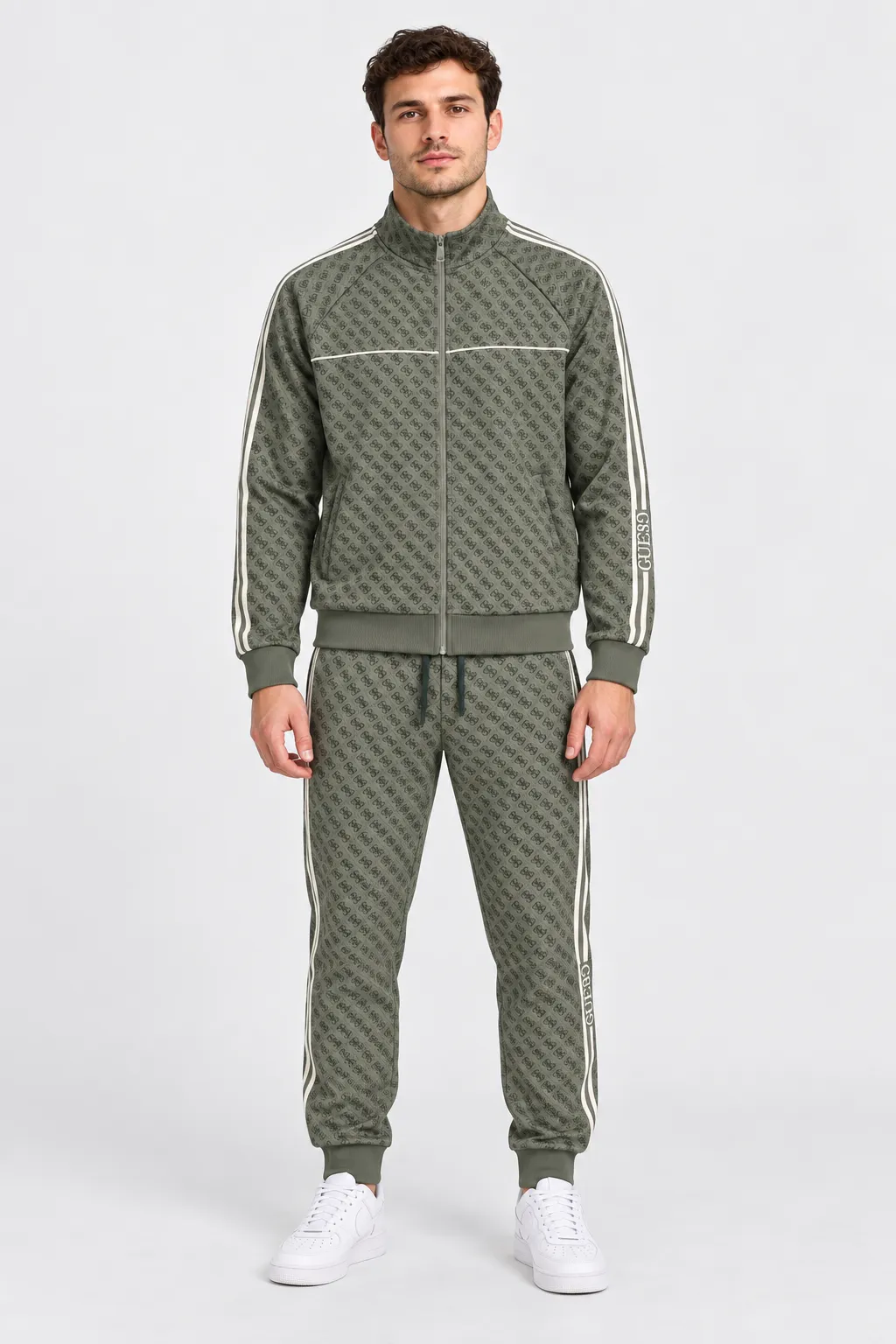 Modello indossa tuta sportiva Follower SRL verde con logo GUESS all-over, giacca con zip e pantaloni jogger
