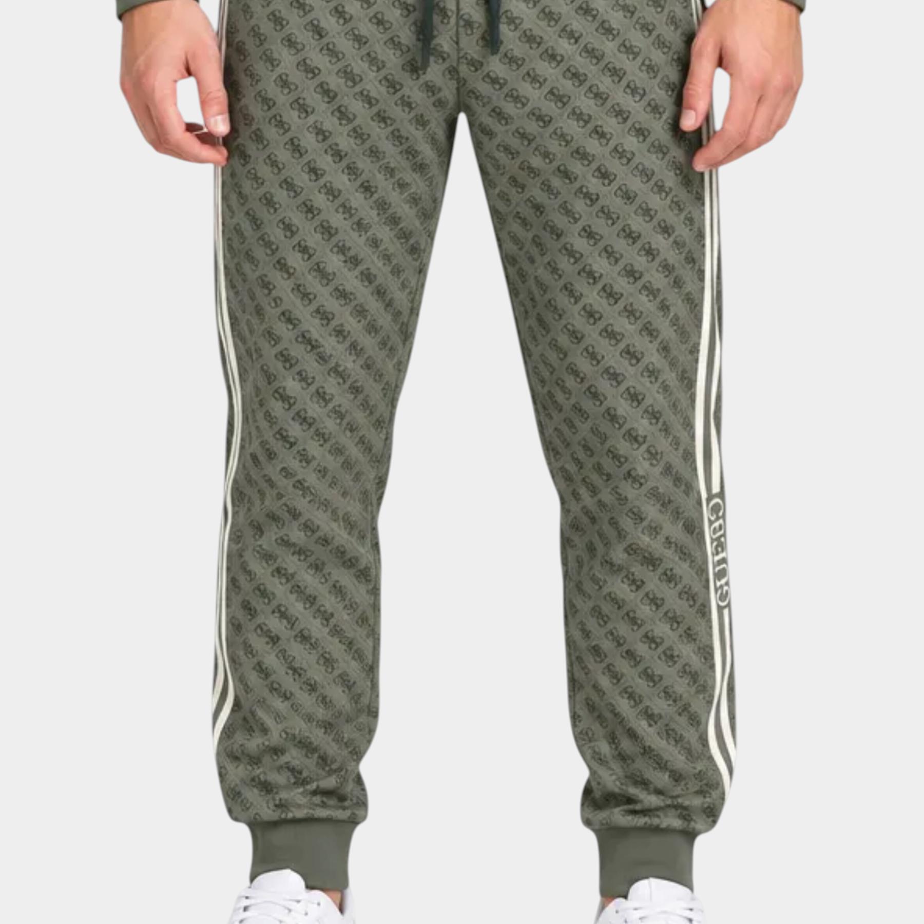 Modello indossa tuta sportiva Follower SRL verde con logo GUESS all-over, giacca con zip e pantaloni jogger