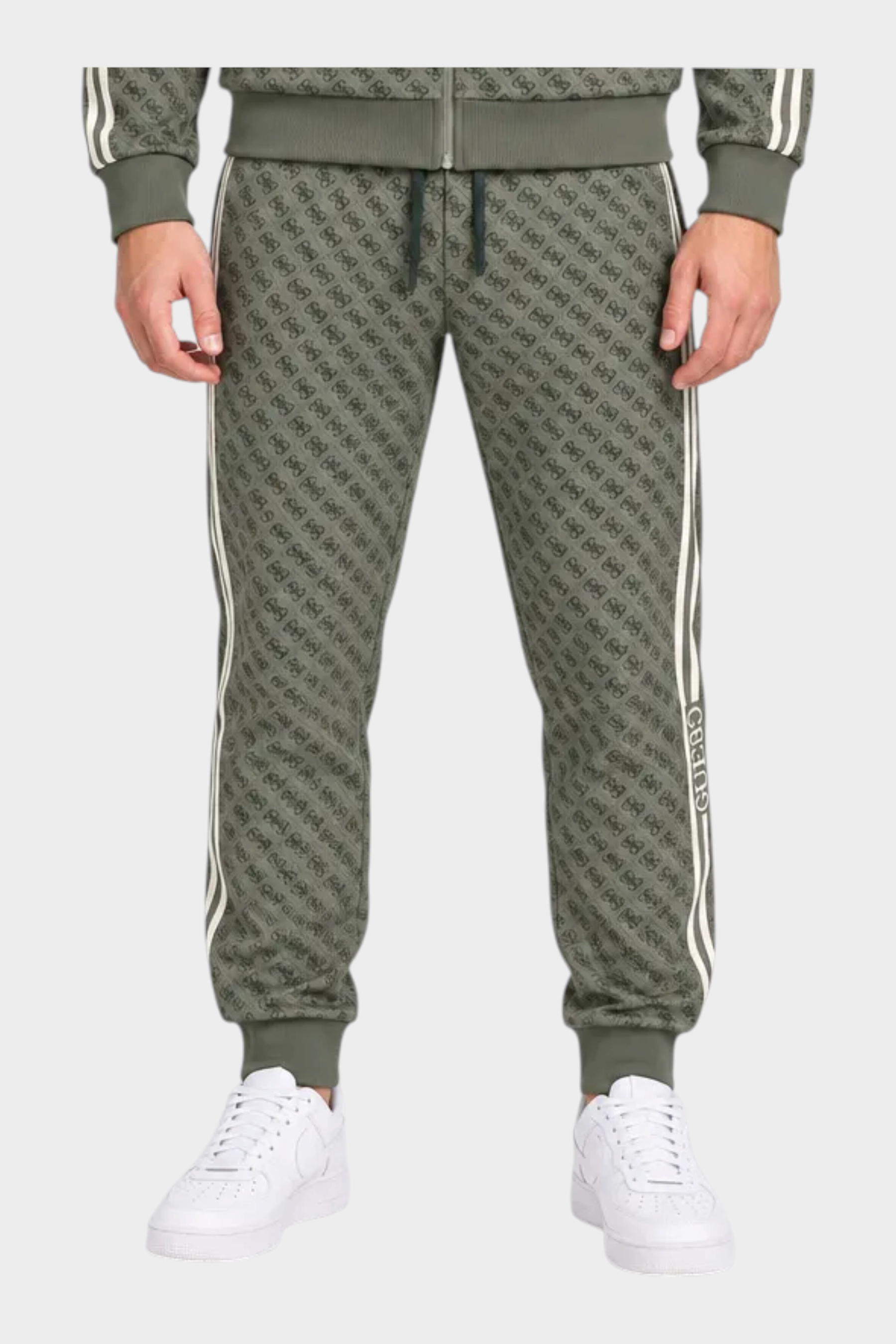 Modello indossa tuta sportiva Follower SRL verde con logo GUESS all-over, giacca con zip e pantaloni jogger