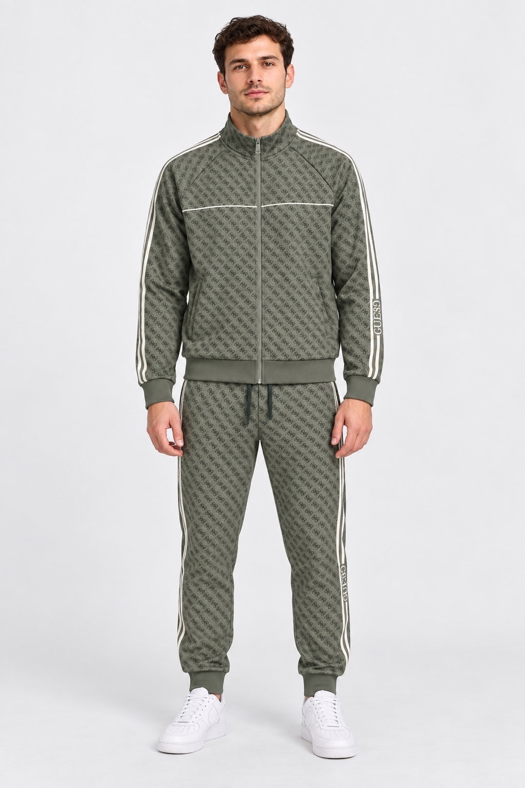 Modello indossa tuta Follower SRL verde con logo GUESS all-over, zip integrale e bande laterali a contrasto