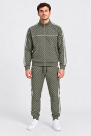 Modello indossa tuta Follower SRL verde con logo GUESS all-over, zip integrale e bande laterali a contrasto