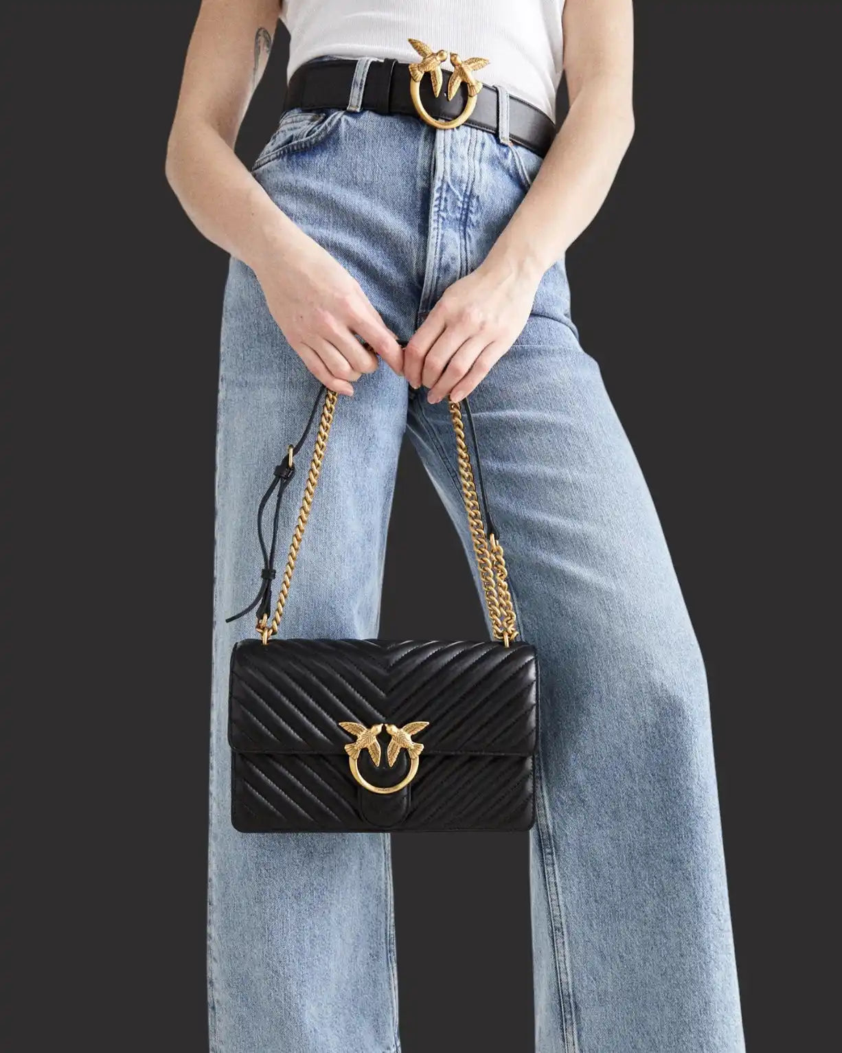 Borsa a tracolla trapuntata nera con charm a forma di ape e tracolla a catena.